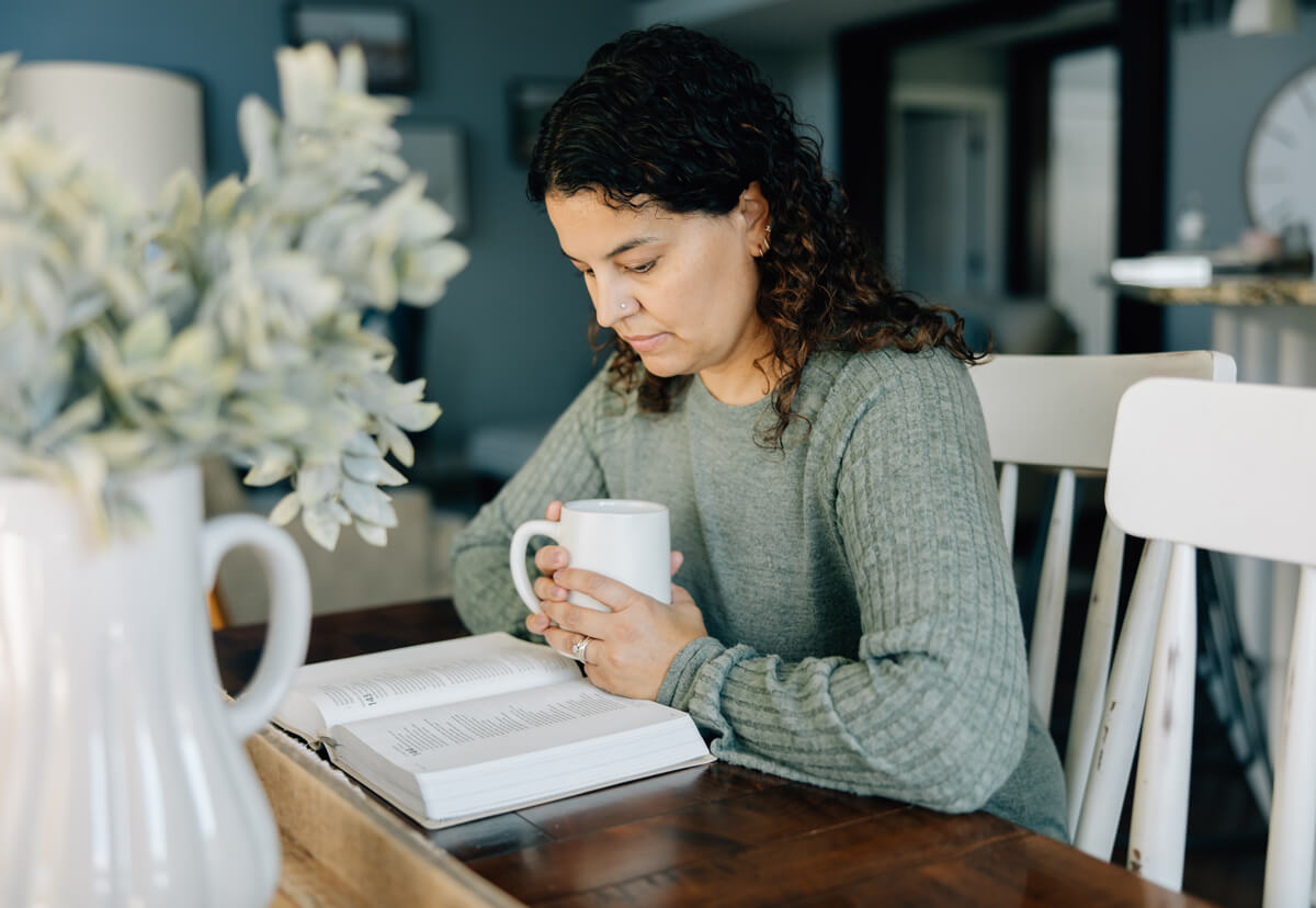 Anastasia sitting reading with a cup of coffee